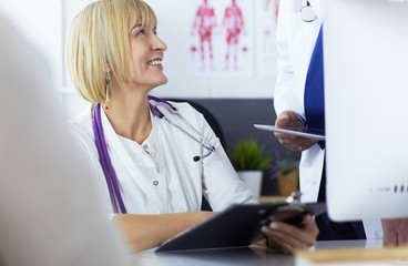 Female doctor sitting at table with laptop, working