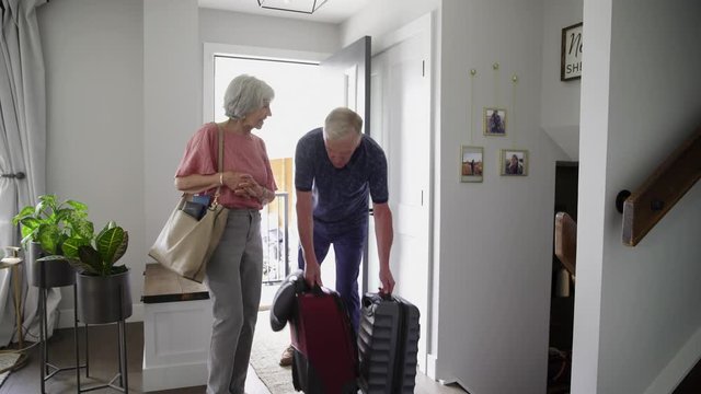 Senior Couple With Suitcases Arriving At House Rental