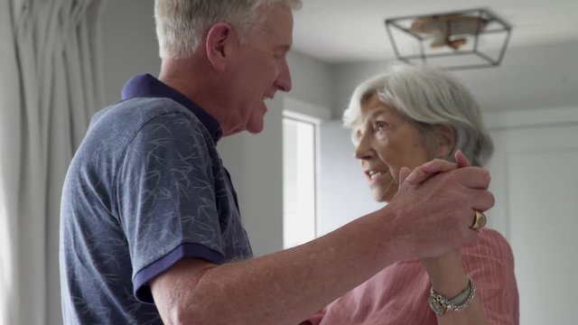 Affectionate senior couple singing and dancing at home