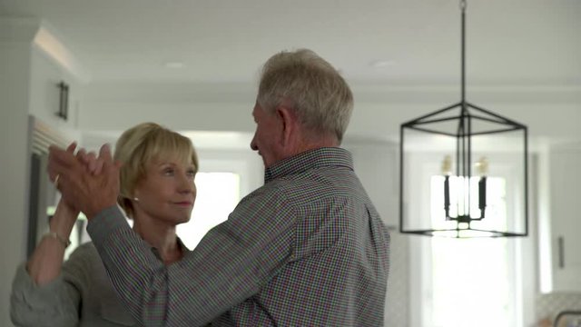 Affectionate senior couple dancing at home