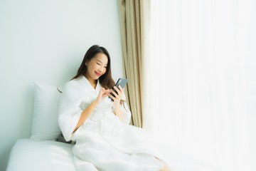 Obraz na płótnie Canvas Young asian woman using mobile smart phone on bed