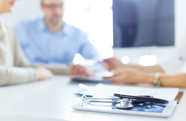 Close up of doctor and patient sitting at the desk near the window in hospital