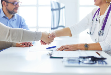 Female doctor shaking a hand in her office