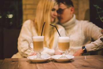 Young happy couple in love in cafe, man and woman together smile hugging, drinking coffee. Couple Talking In Cafe In Winter. Happy couple enjoying a coffee at the coffee shop. Happiness, christmas