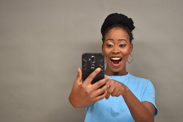 pretty african girl viewing content on her mobile phone feeling happy and excited