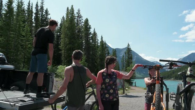 Friends Unloading Mountain Bikes From Pickup Truck Bed At Sunny Lakeside