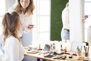 make up artist doing professional make up of young woman