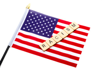 Fototapeta premium The flag of the United States isolated on a white background with a sign reading Racism