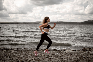 Fototapeta na wymiar Side view young woman running and jumping outdoors