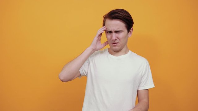 The young husband holds his hand on head wincing in pain