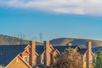 Homes with gray gable roofs and stone brick chimneys against mountain and sky