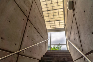 Stairs between interior walls of building leading to glass wall with sky view