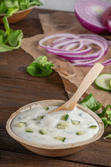 Top view of wooden cutting board on old wooden table top with tablecloth and yogurt sauce dip in a bowl