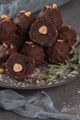 Dark chocolate truffles with hazelnuts on plate.