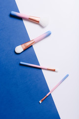 Set of makeup brushes on blue and white colored composed background. Top view point, flat lay.