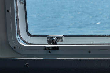 metal latch on a ferry boat window on bright spring day