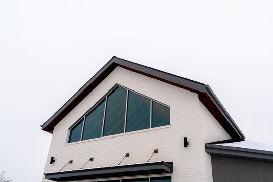 Home exterior with tringular window and white wall under gable roof