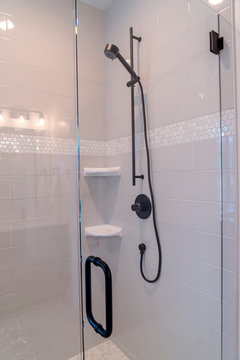 Bathroom Stall With Black Shower Fixture And Soap Dishes Against White Tile Wall