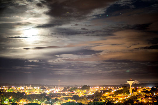 Luar iluminando a cidade em uma noite de nuvens
