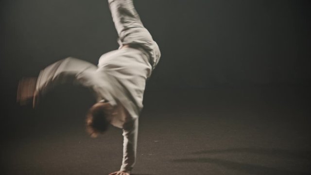 Young man training his dancing in the studio - performing a breakdancing trick