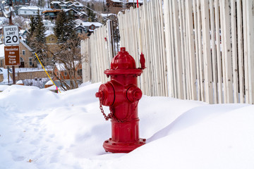 Vibrant red fire hydrant against snow and hill homes at Park City Utah in winter - Powered by Adobe