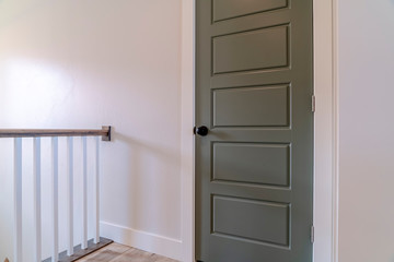 White railing and gray door against white wall of home with wooden floor