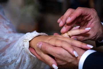 Noivo colocando a aliança no dedo do noiva