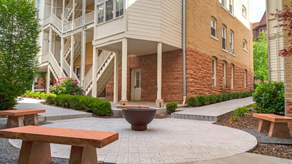 Panorama Fire pit and stone benches against building with stone brick wall and staircases