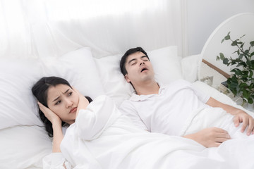 Young couple have problem with man's snoring. Heterosexual couple in bed, man sleeps and snoring...