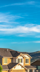 Vertical Houses with view of the roofs and upper storey against hills and vibrant sky