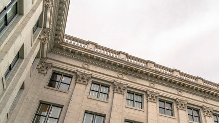Panorama Building with decorative wall mouldings and shiny windows against cloudy sky