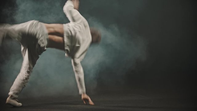 Young man dancer showing breakdance elements tricks in the dark studio