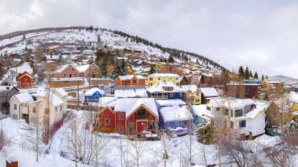 Fototapeta na wymiar Panorama frame Colorful homes and scenic hills blanketed with white snow during winter season