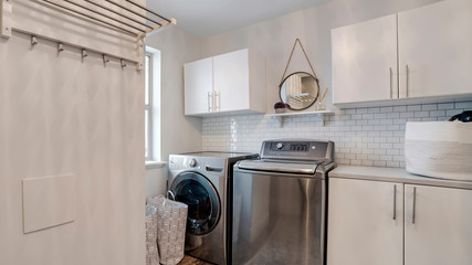 Panorama frame Laundry room interior with cabinets wahing machine and dryer against white wall