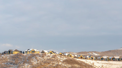 Fototapeta na wymiar Panorama Houses on neighborhood nestled on top of snowy hills viewed in winter