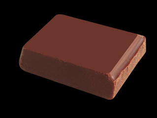 Delicious black chocolate shavings and pieces on the black background, top view