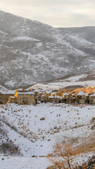 Photo Vertical frame Houses amid hill landscape dusted with fresh white snow on a cold winter day