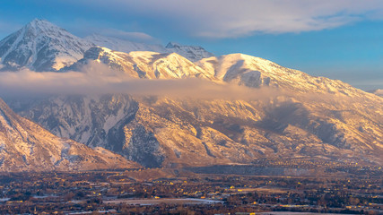 Panorama Mount Timpanogos over homes with snow at winter and illuminated by golden sunset