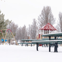 Square frame Thick layer of fresh white snow covering a park with playground and picnic area