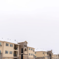 Square frame Facade of homes with snow coated roofs against cloudy sky on a cold winter day