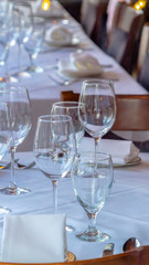 Photo Vertical Wine glasses spoons forks saucer plates and napkins on a table with white cloth