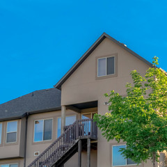 Square frame Home exterior with gable and valley roof against vibrant blue sky on a sunny day