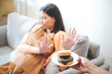 Asian woman pregnant refused to eat donuts, a food that is bad for her unborn child.