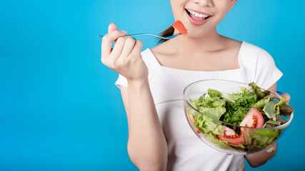 Beautiful young asian eating salad with big smile happy beaming face in seamless blue  isolated background.