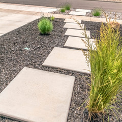 Square Landscaped yard with stone steps pathway that leads to the paved road