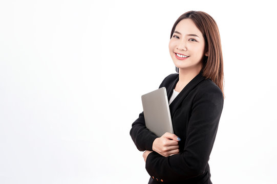 Asian businesswoman with black suit holding a laptop with big smile beaming face in white isolated background.