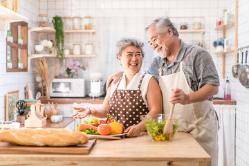 Couple senior Asian elder happy living in home kitchen. Grandfather cooking salad dish with grandmother with happiness and smile enjoy retirement life together. Older people relationship and activity.
