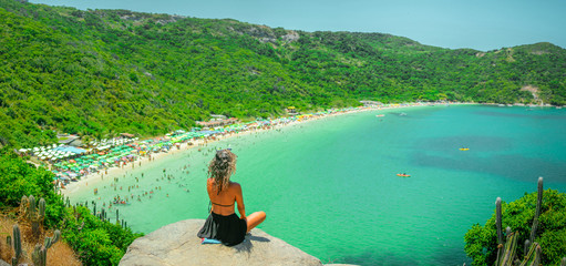 Young woman sitting looking at a heavenly beach with crystal clear waters