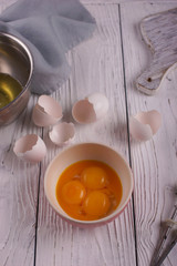 Egg yolks separated from proteins in a bowl on a white wooden background