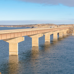 Square Blue lake with bridge connecting vast terrains blanketed with snow in winter